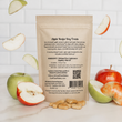 Load image into Gallery viewer, Back of the dog treat package with apple recipe text, surrounded by apples and treats on a white kitchen background
